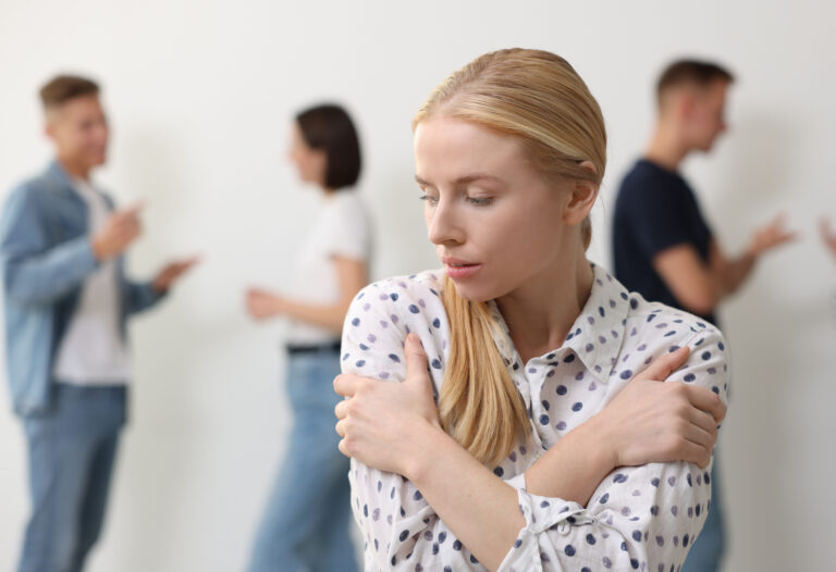 Young woman feeling uncomfortable among people indoors, selective focus